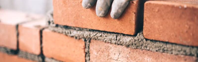 Close up of industrial bricklayer installing bricks on construction site